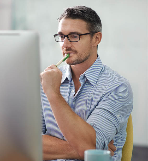Mężczyzna wpatruje się w ekran komputera, zastanawiając się nad zadaniem, które ma do wykonania.